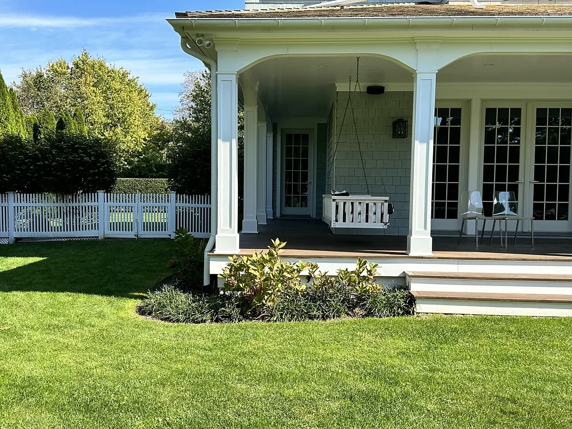 A white house with a porch and a white fence