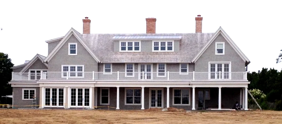 A large gray house sitting on top of a dry grass field