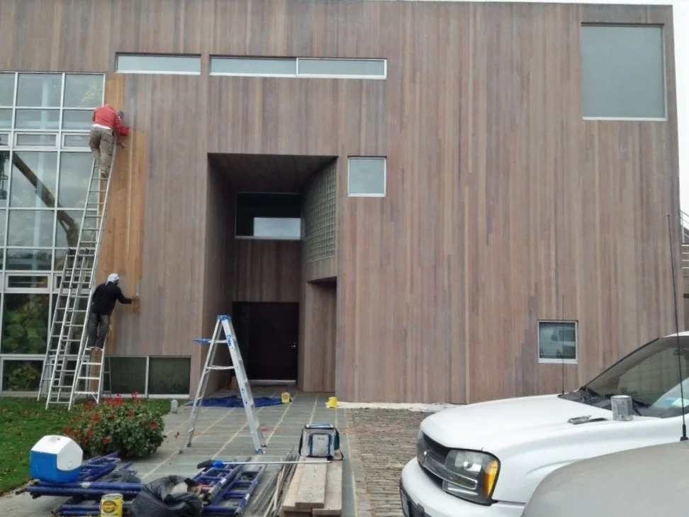 A man on a ladder painting a wooden building